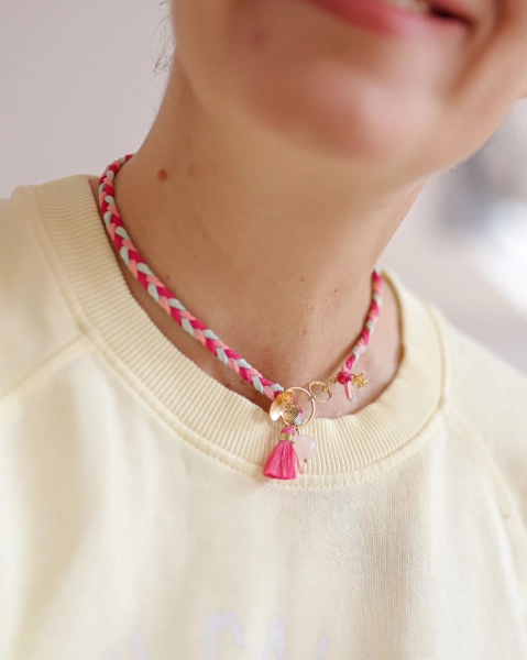 Pleciona biżuteria ByLucy noszona jako choker z kwarcem różowym, pozłacanymi kwiatami i chwostem.